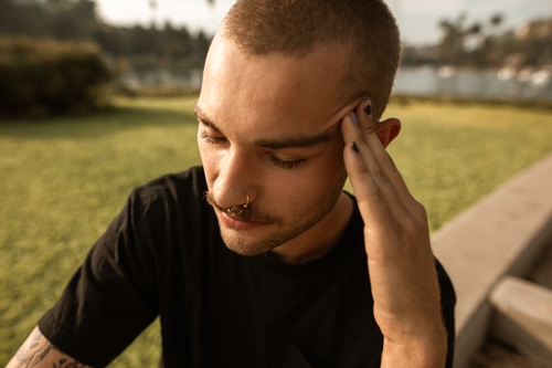 man zit buiten met hoofdpijn